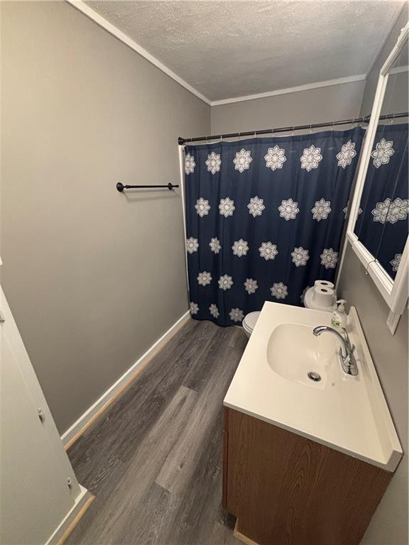 bathroom with hardwood / wood-style flooring, crown molding, a textured ceiling, and toilet