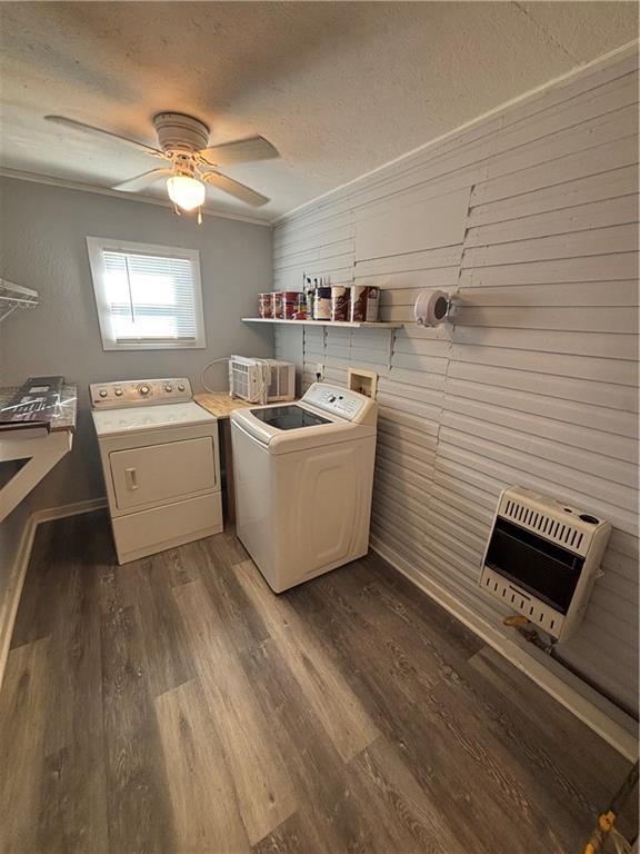 clothes washing area with heating unit, ornamental molding, separate washer and dryer, and wood walls