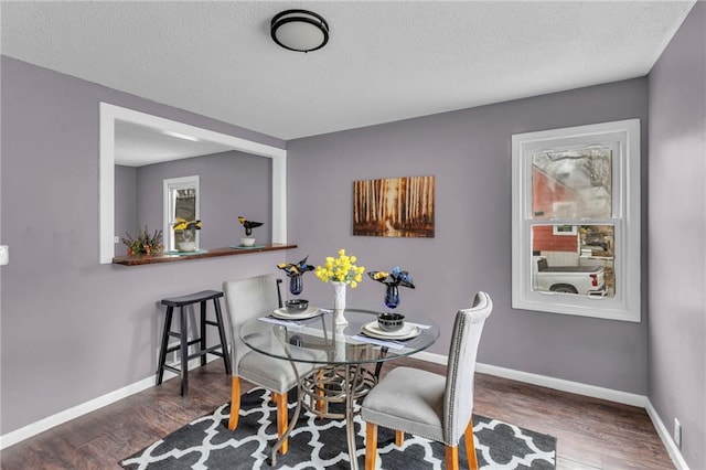 dining area featuring dark hardwood / wood-style flooring and a textured ceiling