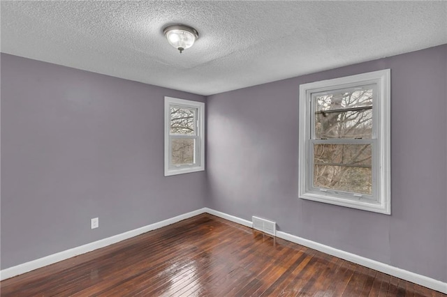 unfurnished room featuring dark wood-type flooring and a textured ceiling