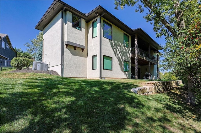 back of property featuring a balcony, a lawn, and central air condition unit