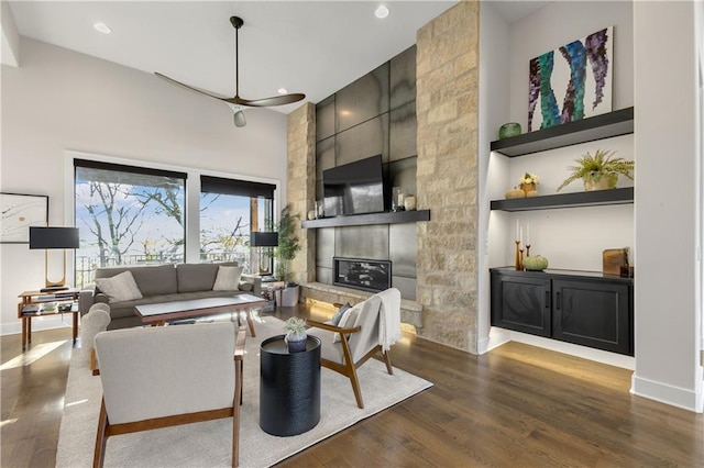 living room featuring dark wood-type flooring, a towering ceiling, and a tile fireplace