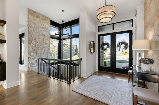 foyer featuring french doors, a healthy amount of sunlight, dark hardwood / wood-style floors, and a notable chandelier