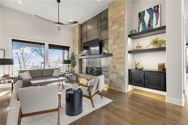 living room featuring a large fireplace, dark hardwood / wood-style floors, and a towering ceiling