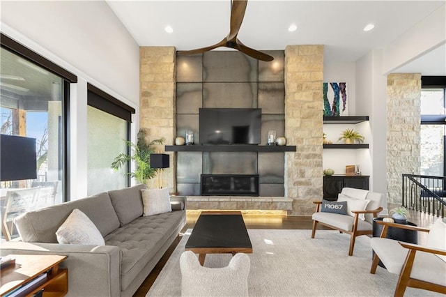 living room featuring wood-type flooring, ceiling fan, and a fireplace