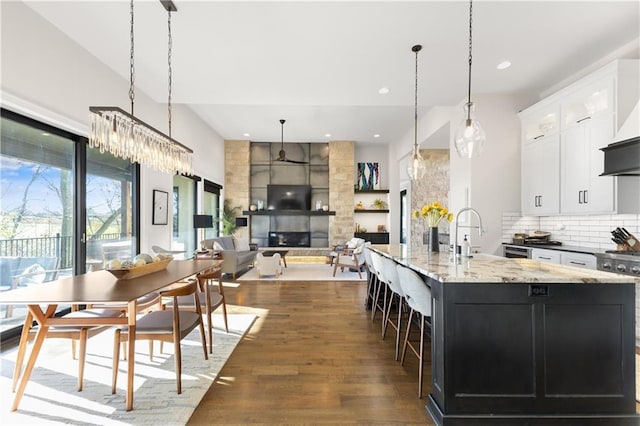 kitchen featuring dark hardwood / wood-style floors, a fireplace, decorative light fixtures, white cabinetry, and a spacious island