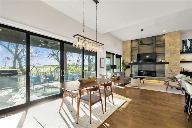 dining space with hardwood / wood-style flooring, a fireplace, and a high ceiling