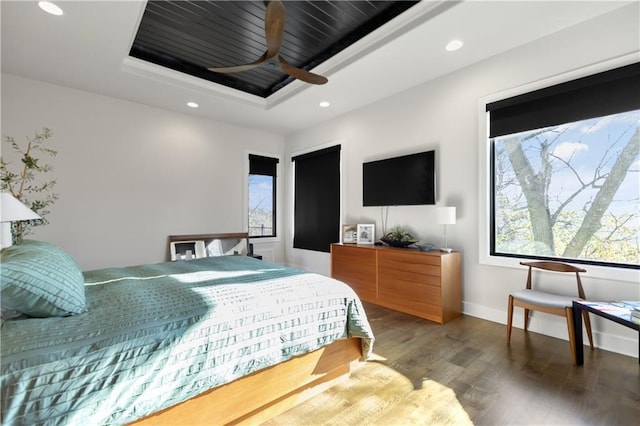 bedroom with wood-type flooring, a raised ceiling, and ceiling fan