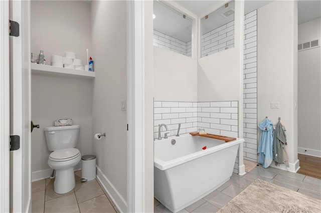 bathroom with tile patterned floors, toilet, and a washtub