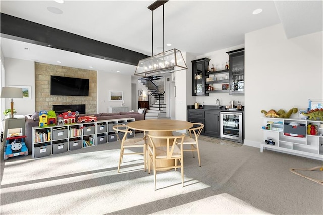 carpeted dining space with wine cooler, beam ceiling, a fireplace, and wet bar