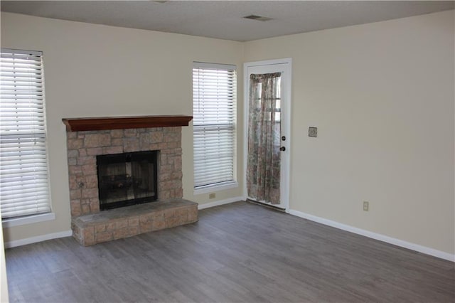 unfurnished living room with a stone fireplace and dark hardwood / wood-style flooring