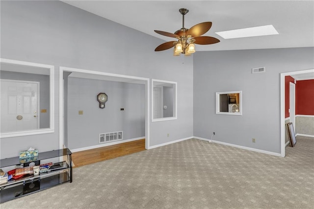 living room with high vaulted ceiling, light carpet, ceiling fan, and a skylight