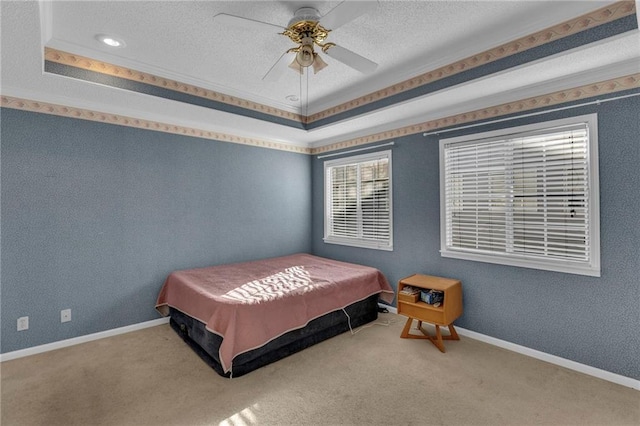 bedroom featuring a raised ceiling, ceiling fan, carpet flooring, and a textured ceiling