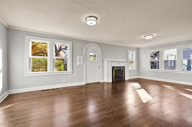 unfurnished living room featuring ornamental molding, plenty of natural light, and dark hardwood / wood-style floors