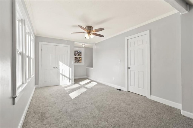 unfurnished bedroom with crown molding, ceiling fan, light colored carpet, and multiple windows