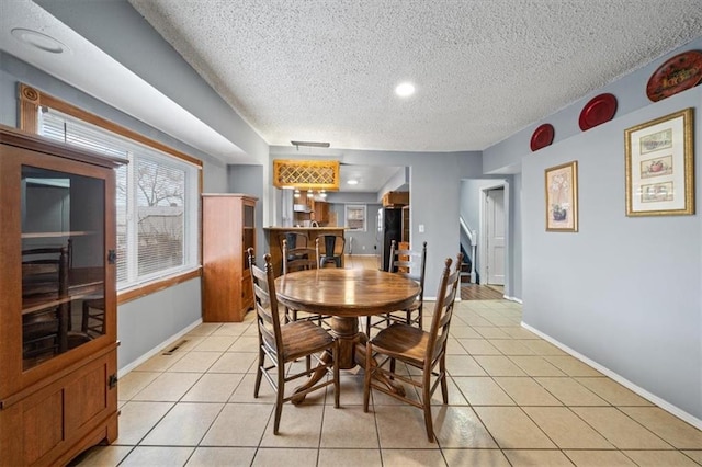 dining space featuring light tile patterned flooring, plenty of natural light, a textured ceiling, and baseboards