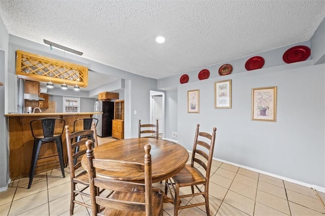 dining room featuring a textured ceiling, baseboards, and light tile patterned floors