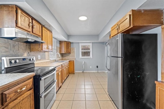 kitchen featuring light tile patterned flooring, under cabinet range hood, light countertops, appliances with stainless steel finishes, and backsplash