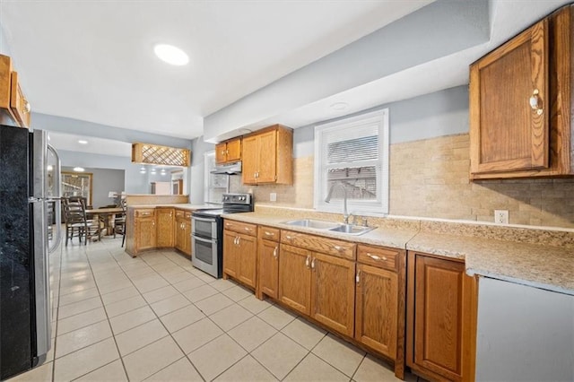 kitchen with range with two ovens, freestanding refrigerator, a peninsula, light countertops, and a sink