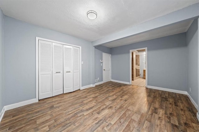 unfurnished bedroom with a closet, baseboards, and wood finished floors