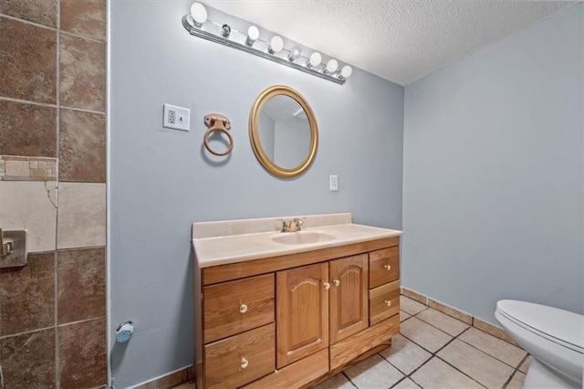 bathroom featuring baseboards, toilet, tile patterned flooring, a textured ceiling, and vanity