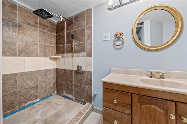 bathroom with a textured ceiling, a tile shower, vanity, and tile patterned floors