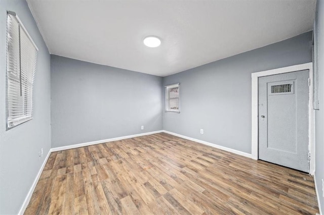 spare room with wood finished floors, visible vents, and baseboards