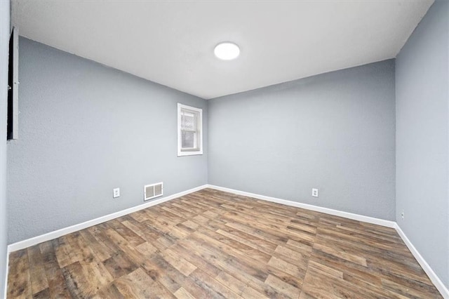 empty room featuring visible vents, baseboards, and wood finished floors