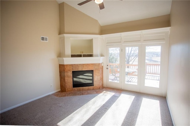 unfurnished living room with a tiled fireplace, vaulted ceiling, light colored carpet, and ceiling fan