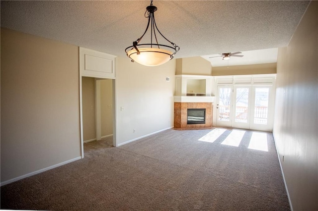 unfurnished living room with lofted ceiling, ceiling fan, carpet flooring, a textured ceiling, and a tiled fireplace