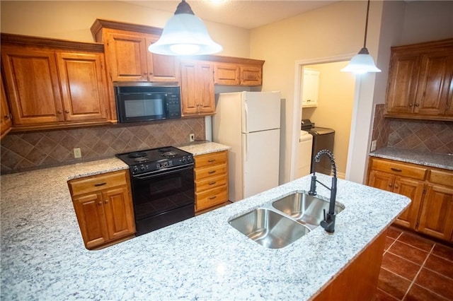 kitchen featuring sink, decorative backsplash, hanging light fixtures, black appliances, and washing machine and dryer