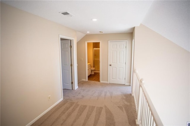 hall featuring light colored carpet and lofted ceiling