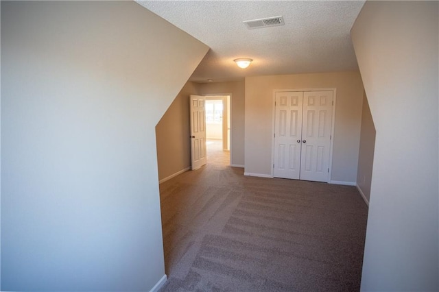 bonus room with carpet floors and a textured ceiling