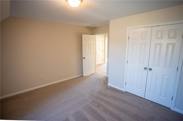 unfurnished bedroom with light colored carpet, a closet, and a textured ceiling