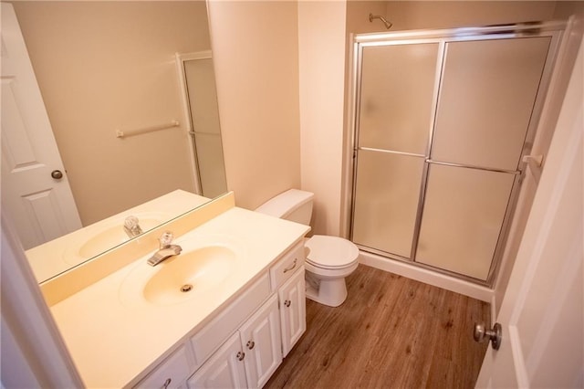 bathroom with a shower with door, vanity, hardwood / wood-style floors, and toilet