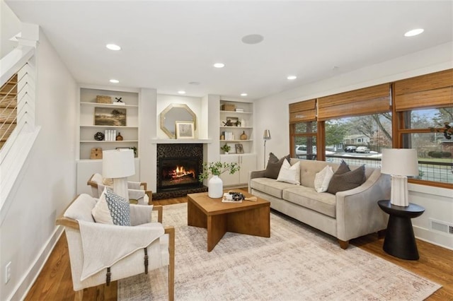 living room featuring built in features and light hardwood / wood-style floors