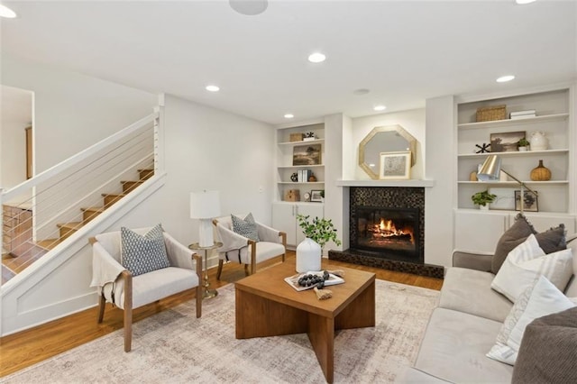 living room featuring built in shelves and light hardwood / wood-style flooring