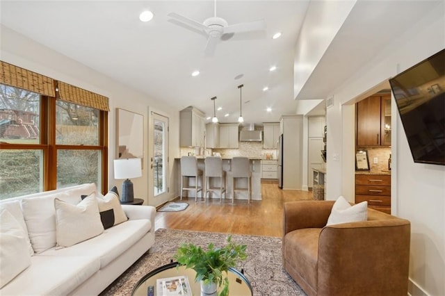 living room featuring ceiling fan, light hardwood / wood-style floors, and vaulted ceiling