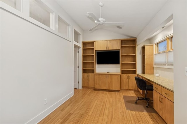 unfurnished office featuring ceiling fan, lofted ceiling, built in desk, and light wood-type flooring