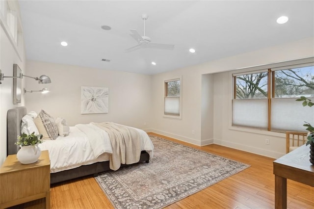 bedroom featuring multiple windows, hardwood / wood-style floors, and ceiling fan