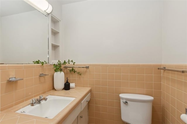 bathroom featuring vanity, tile walls, and toilet