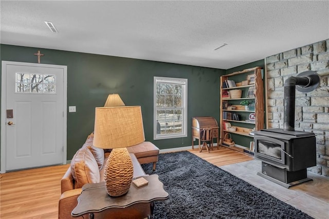 living room with wood-type flooring, a wood stove, and a textured ceiling