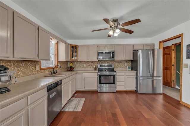 kitchen featuring dark wood-type flooring, sink, tasteful backsplash, appliances with stainless steel finishes, and ceiling fan