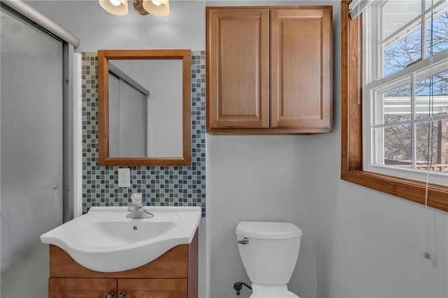 bathroom with vanity, toilet, an enclosed shower, and decorative backsplash