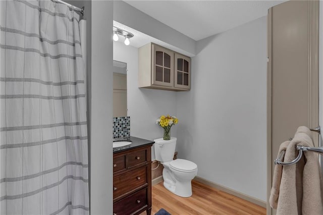 bathroom with walk in shower, vanity, toilet, and wood-type flooring