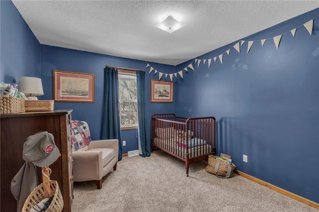 carpeted bedroom featuring a nursery area and a textured ceiling