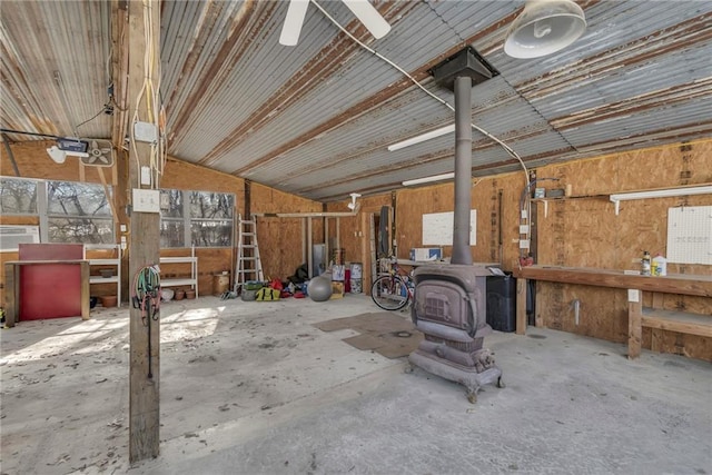 miscellaneous room with concrete flooring, lofted ceiling, a workshop area, and a wood stove