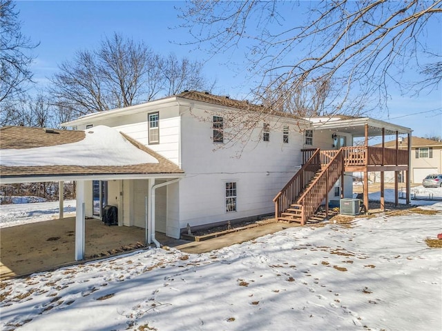 snow covered rear of property with a wooden deck and central AC