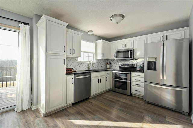 kitchen featuring stainless steel appliances, white cabinetry, sink, and dark hardwood / wood-style floors