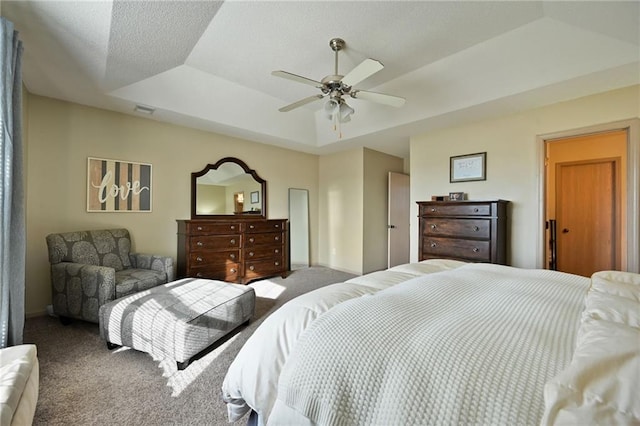 carpeted bedroom featuring a raised ceiling and ceiling fan